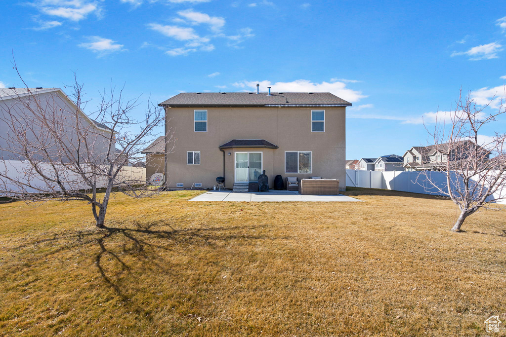 Rear view of property featuring stucco siding, a patio area, fence, and a lawn