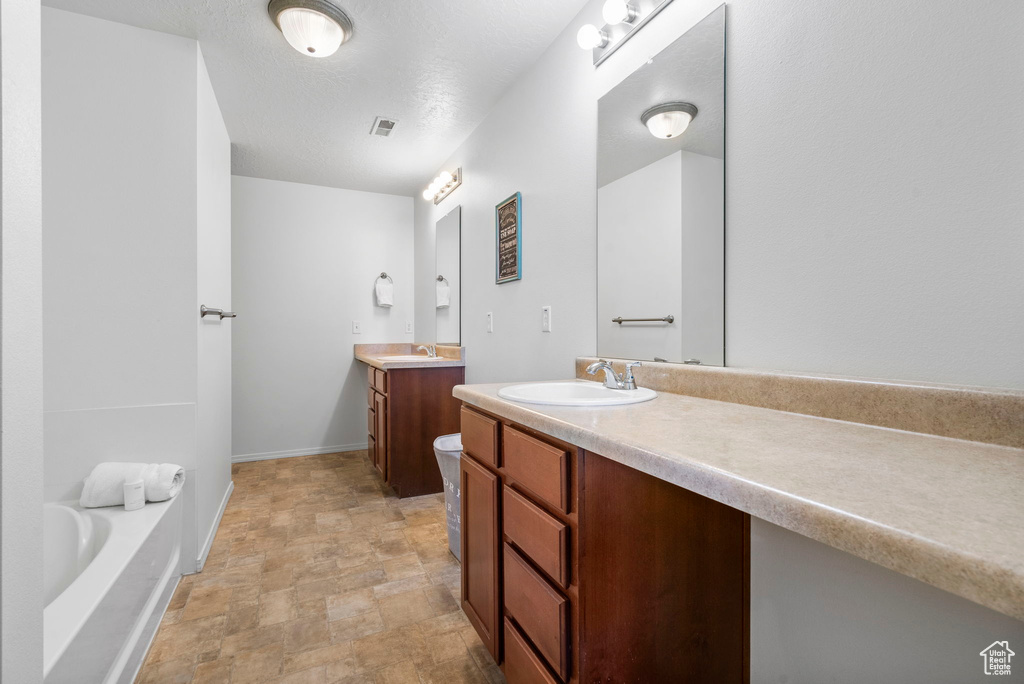 Bathroom with stone finish floor, two vanities, a sink, and baseboards