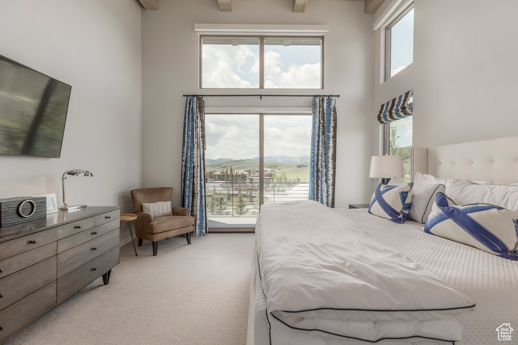Bedroom featuring a towering ceiling, light carpet, and access to outside
