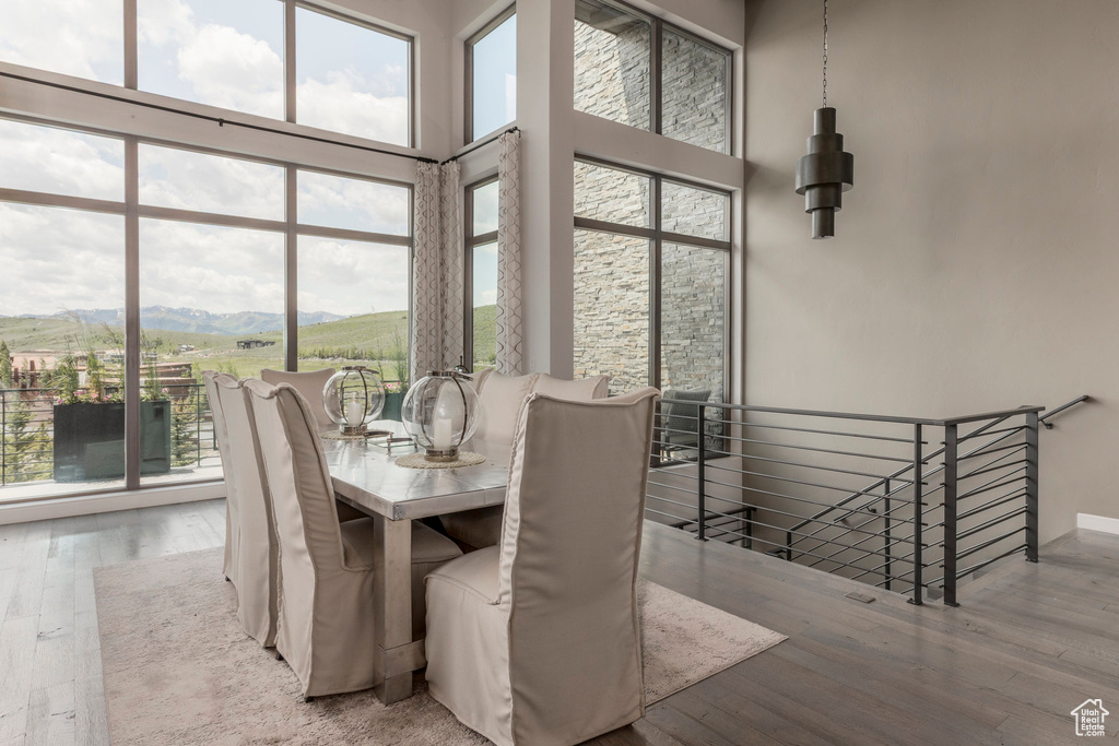 Dining area with plenty of natural light, a towering ceiling, wood finished floors, and a mountain view