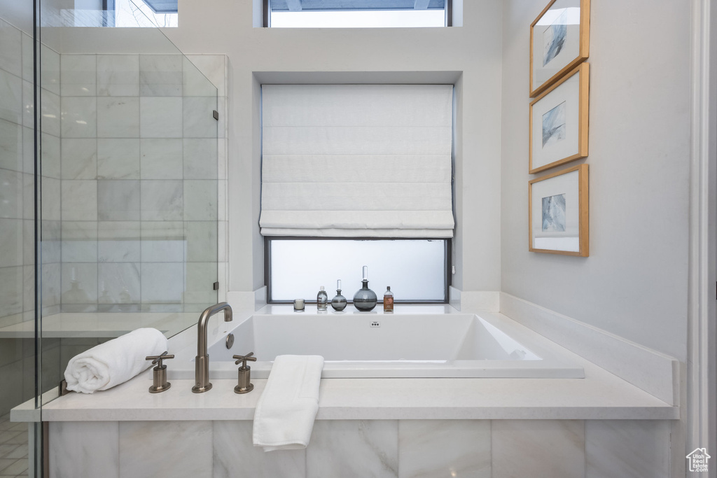 Full bath featuring plenty of natural light, a bath, and a shower stall