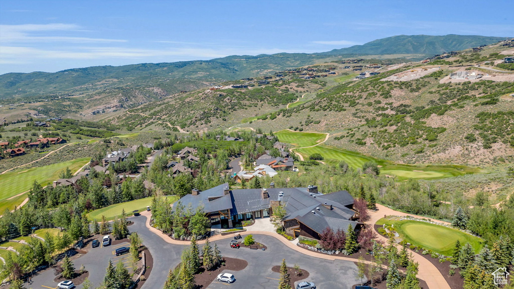 Aerial overview of property's location with a local golf course, mountains, and nearby suburban area