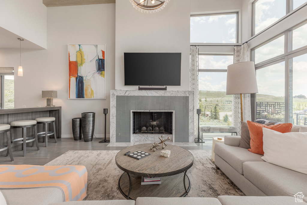 Living room featuring a towering ceiling, wood finished floors, and a high end fireplace