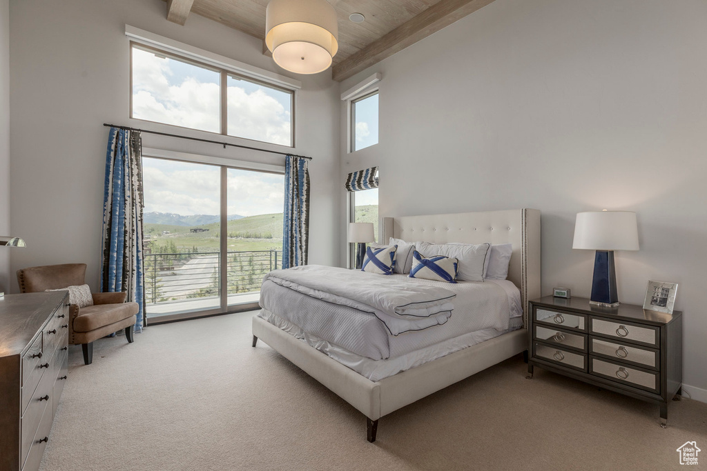 Bedroom featuring light carpet, access to outside, a towering ceiling, and wood ceiling