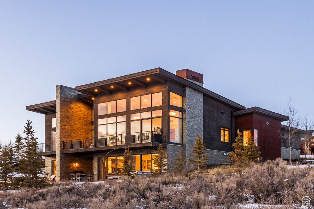 View of property exterior with a chimney, stone siding, and a balcony