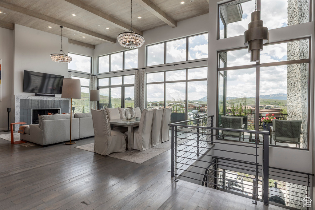 Dining space with a high ceiling, healthy amount of natural light, hardwood / wood-style floors, a chandelier, and a wood ceiling with exposed beams