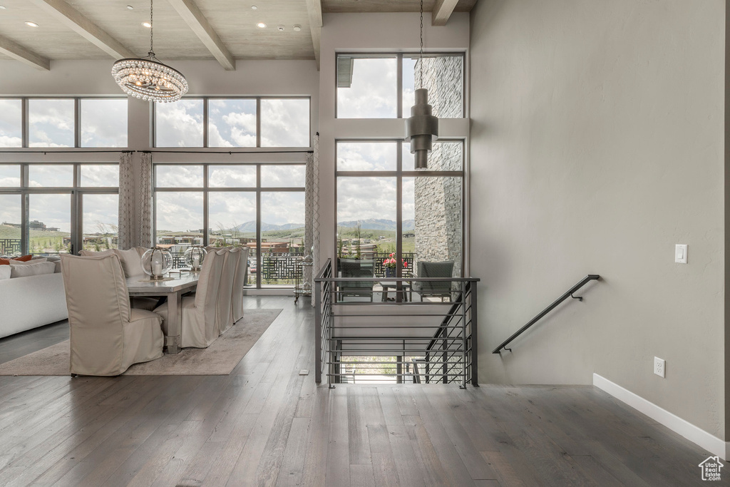 Dining space with beam ceiling, wood-type flooring, a chandelier, a towering ceiling, and a mountain view