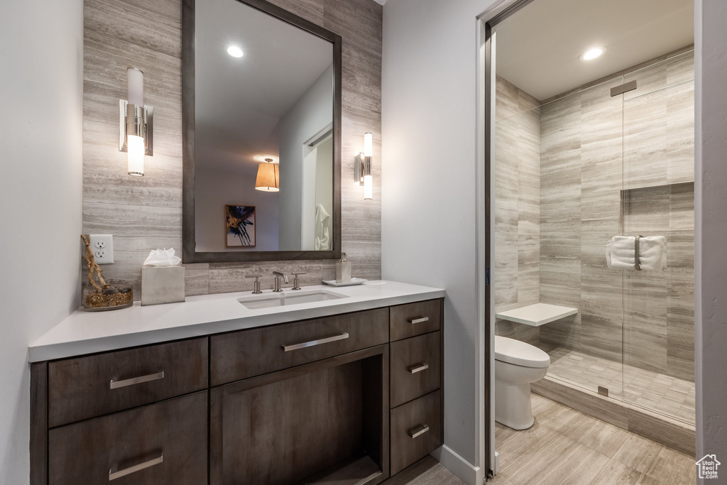 Bathroom featuring vanity, a shower stall, wood finished floors, backsplash, and recessed lighting