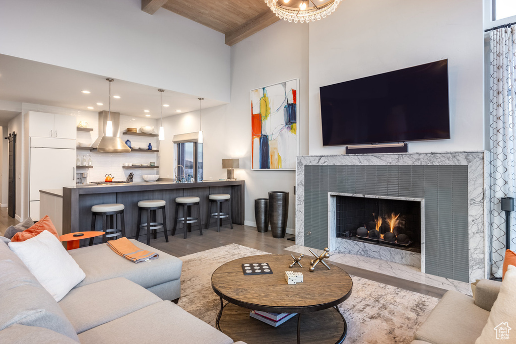 Living room featuring wood finished floors, a wood ceiling with exposed beams, a high ceiling, a fireplace, and recessed lighting