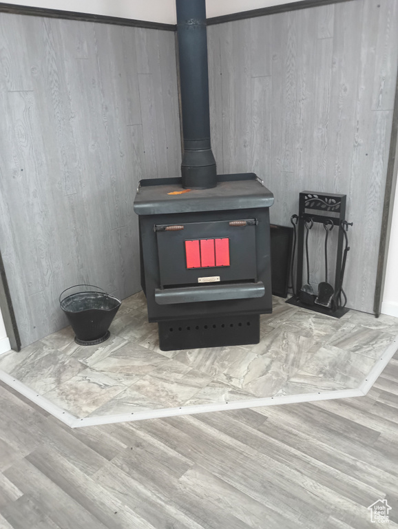 Room details with a wood stove and wood finished floors