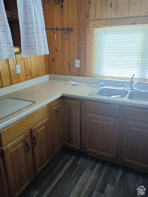 Kitchen with light countertops, a sink, dark wood finished floors, and wooden walls