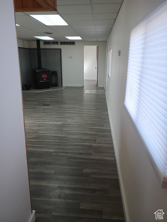 Spare room featuring a wood stove, a drop ceiling, baseboards, and wood finished floors