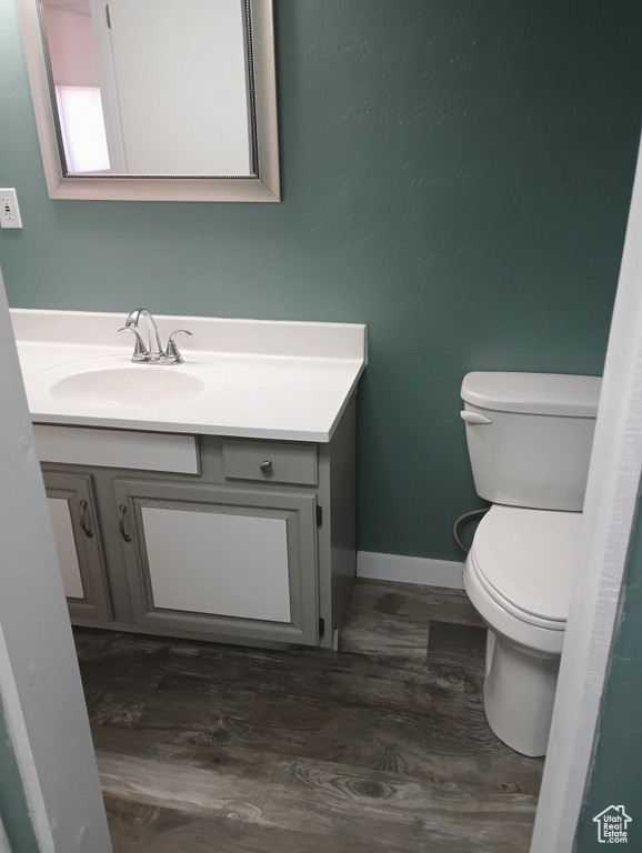 Bathroom featuring baseboards, vanity, toilet, and wood finished floors