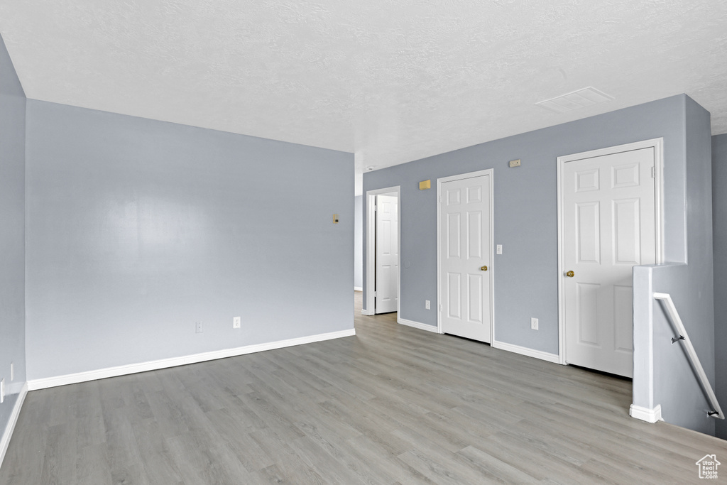 Unfurnished bedroom featuring light wood finished floors, baseboards, and a textured ceiling