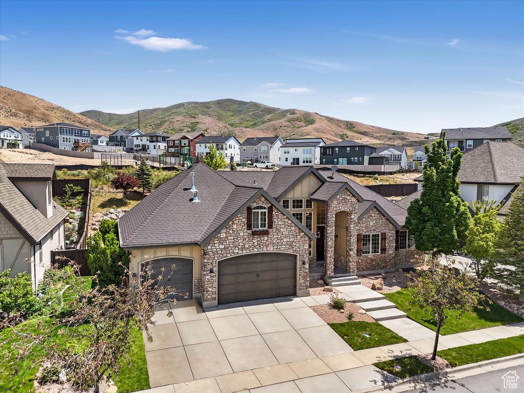 View of front facade with stone siding, a mountain view, a residential view, and driveway