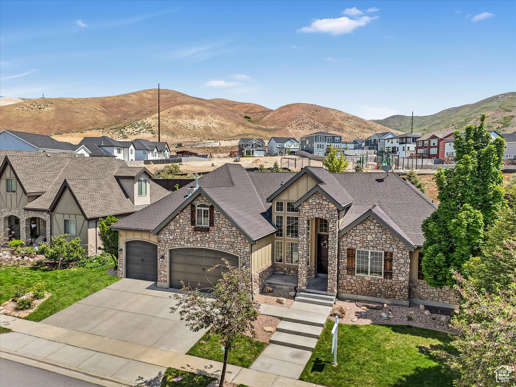 View of front of property featuring stone siding, board and batten siding, a residential view, roof with shingles, and a mountain view