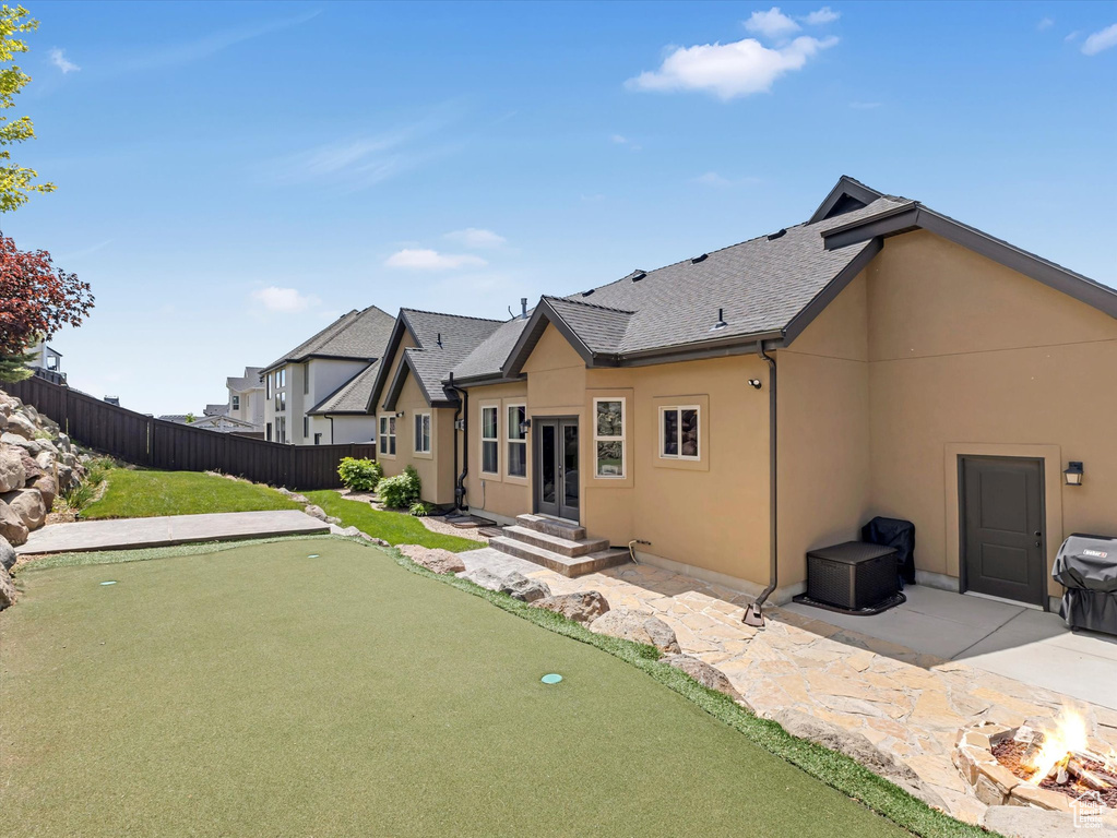Back of house featuring an area to practice putting, an outdoor fire pit, french doors, stucco siding, and a patio area