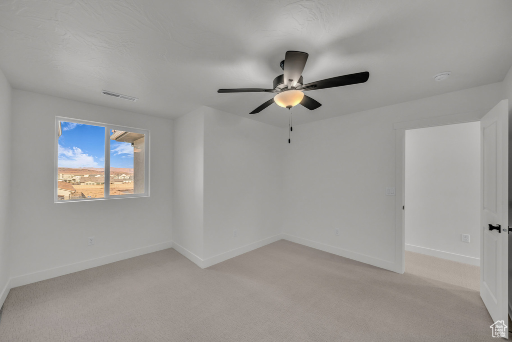 Unfurnished room featuring light colored carpet, visible vents, ceiling fan, and baseboards