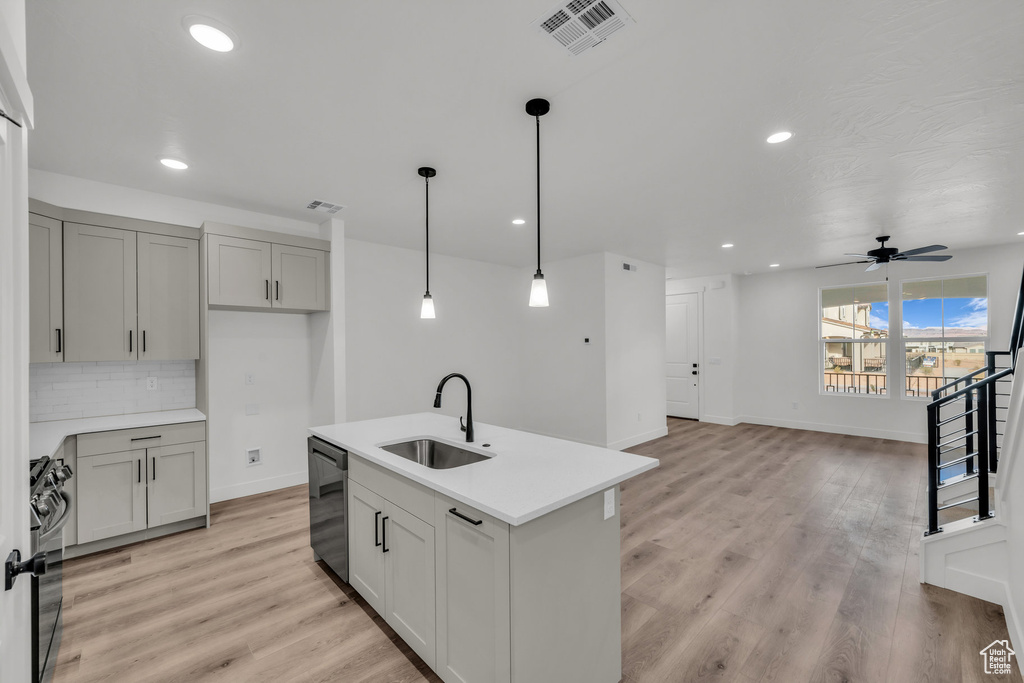 Kitchen with visible vents, decorative backsplash, dishwashing machine, stove, and a sink