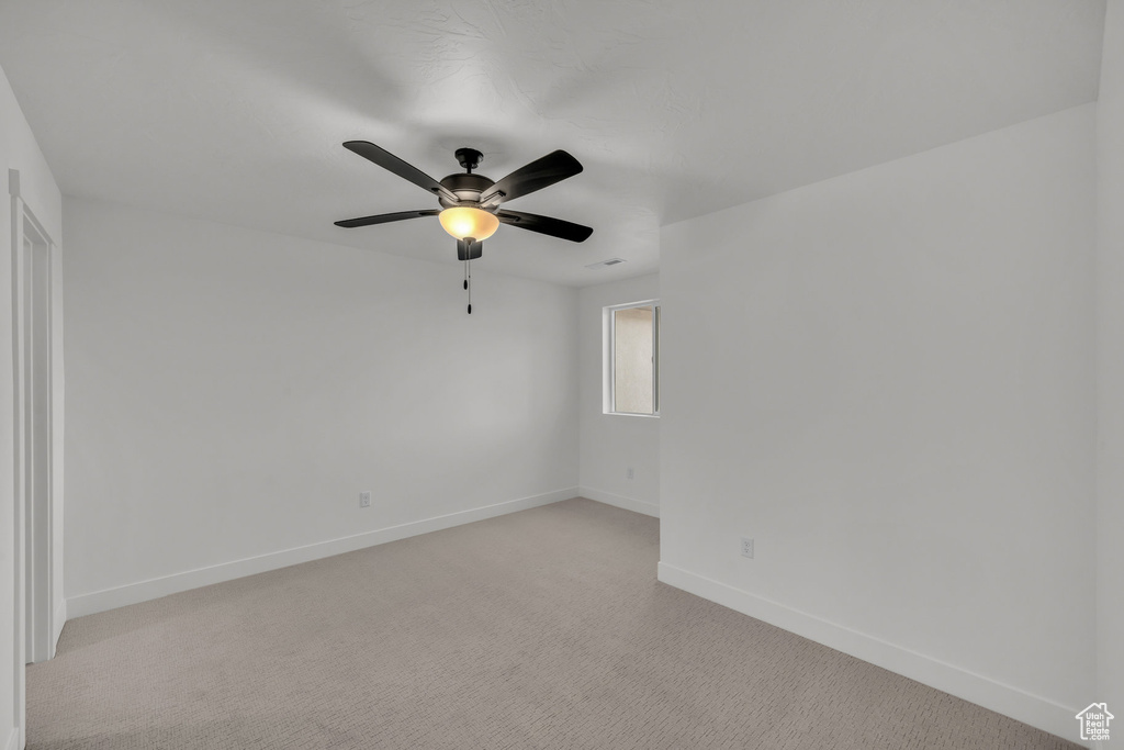 Empty room with ceiling fan, baseboards, and light colored carpet