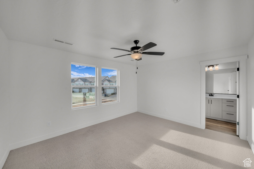 Unfurnished bedroom with ceiling fan, connected bathroom, light colored carpet, visible vents, and baseboards