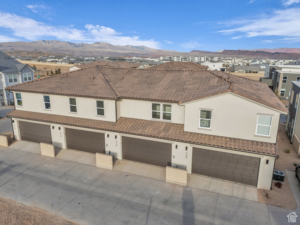 View of front of home featuring concrete driveway, a mountain view, a tiled roof, and stucco siding