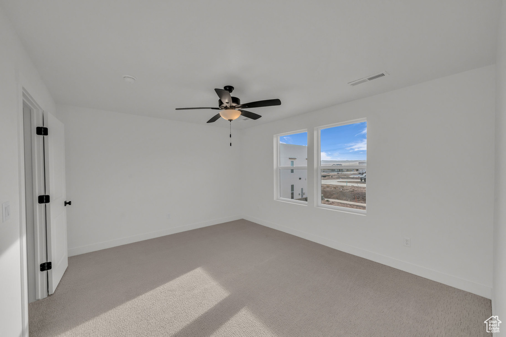 Unfurnished room with light carpet, ceiling fan, visible vents, and baseboards