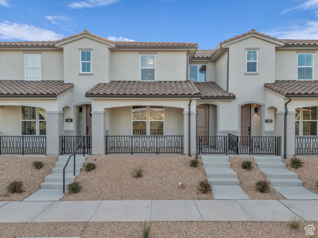 View of front of home featuring a tiled roof, a porch, and stucco siding