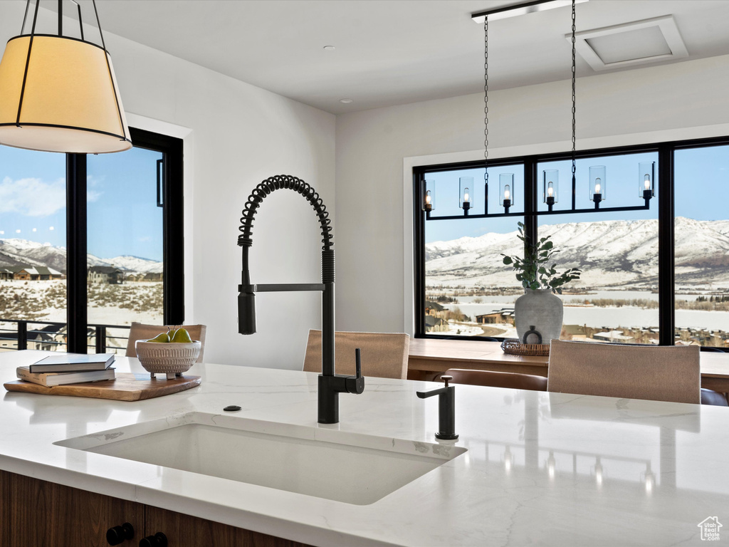 Details with an inviting chandelier, a mountain view, light stone counters, and a sink