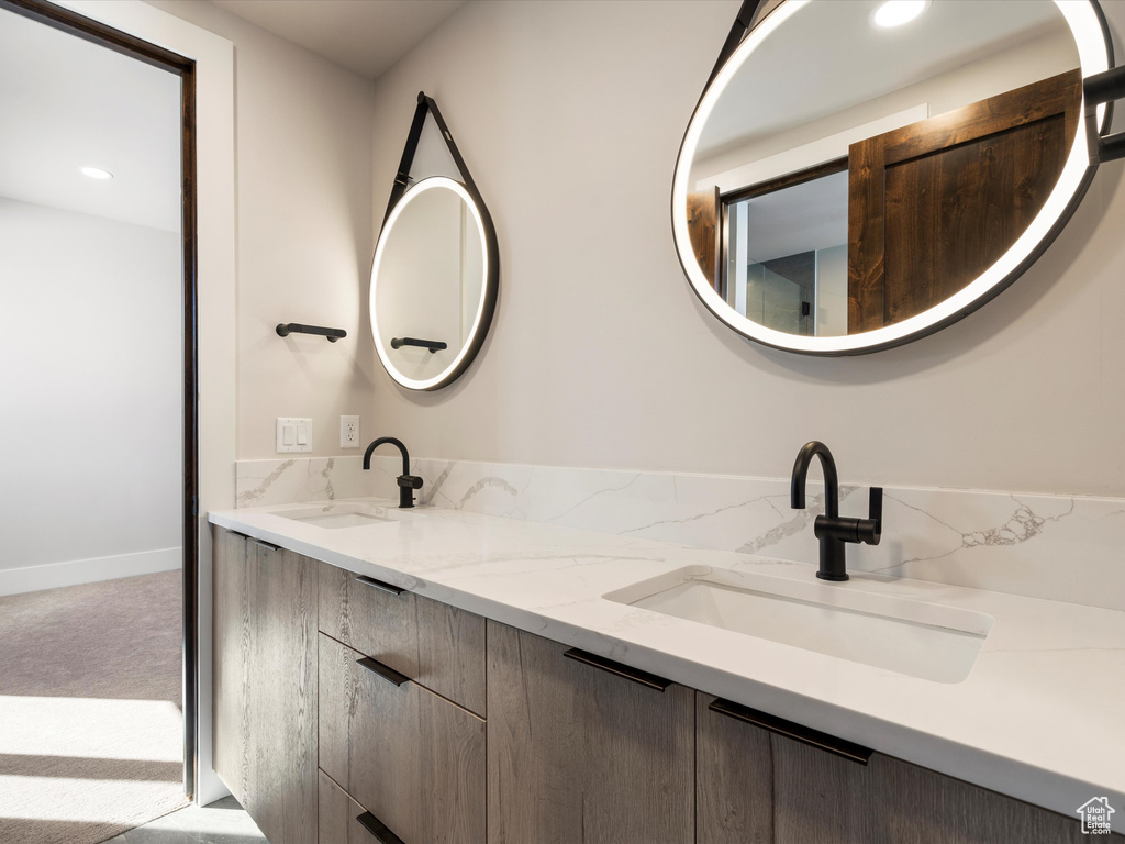 Full bath with baseboards, double vanity, a sink, and recessed lighting