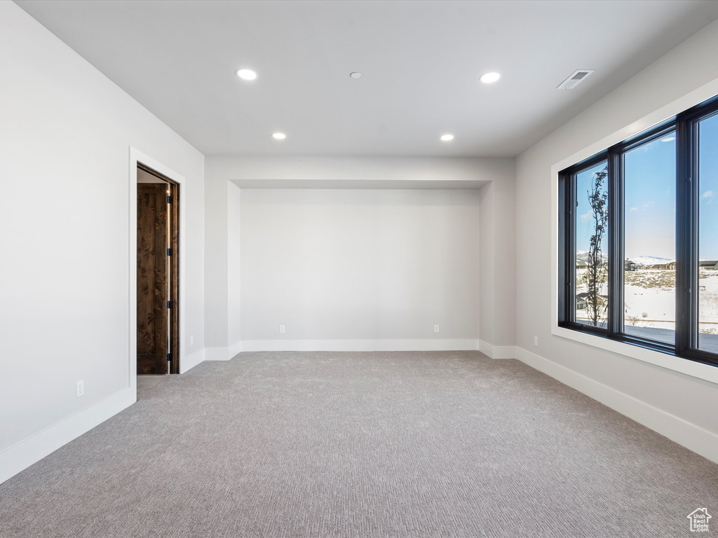 Carpeted empty room featuring baseboards, visible vents, and recessed lighting