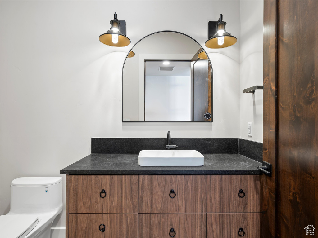 Bathroom featuring toilet, visible vents, and vanity