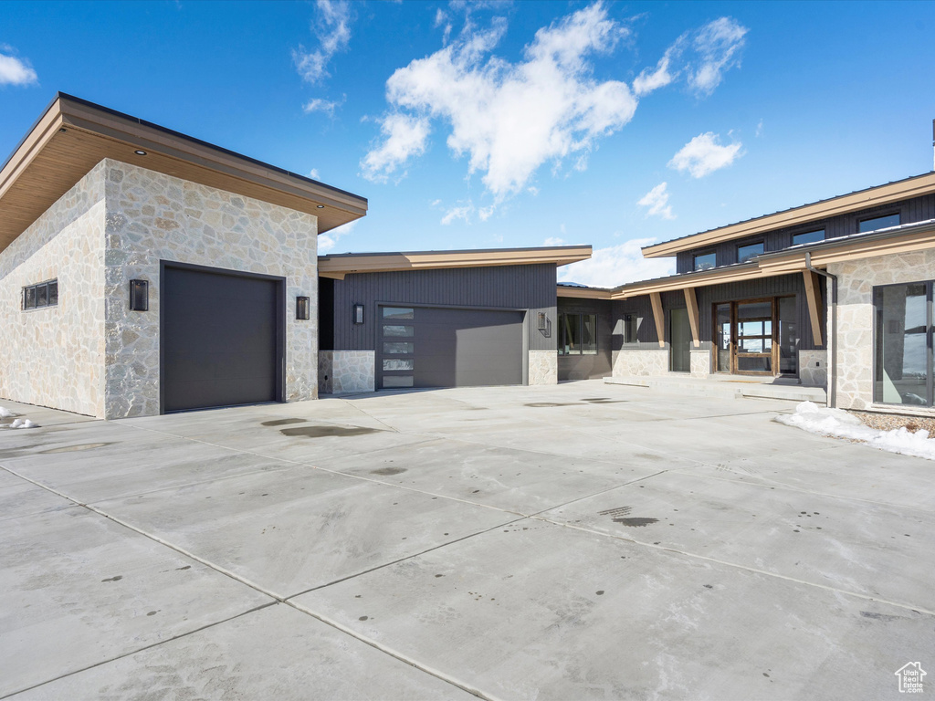 View of side of property with a garage, stone siding, and driveway