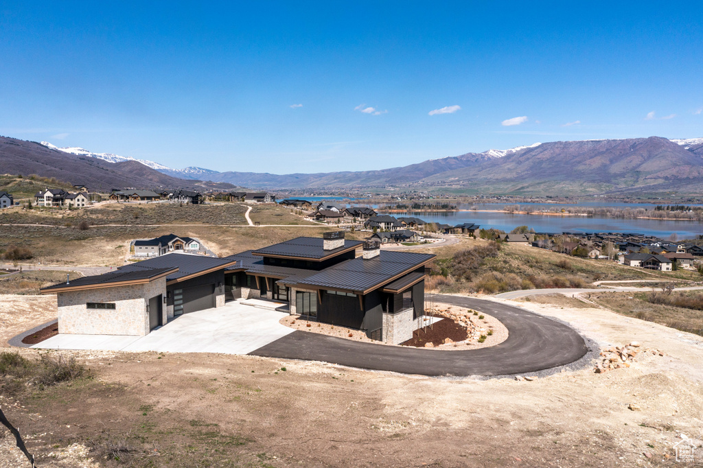 View of front of property featuring metal roof, driveway, a water and mountain view, and an attached garage