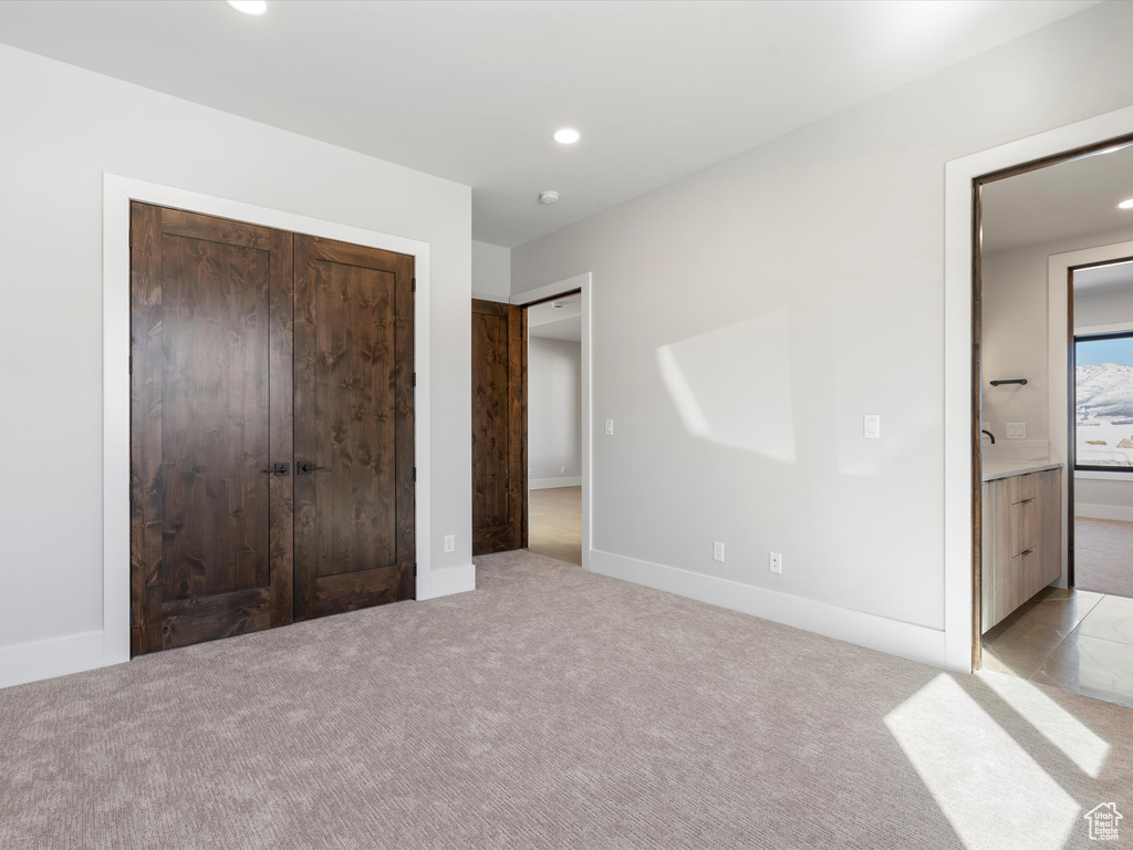 Unfurnished bedroom with recessed lighting, a closet, light carpet, and baseboards