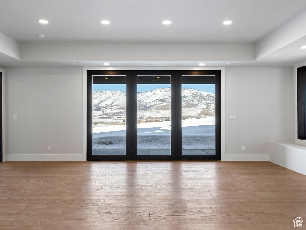 Unfurnished room featuring baseboards, a mountain view, wood finished floors, and recessed lighting