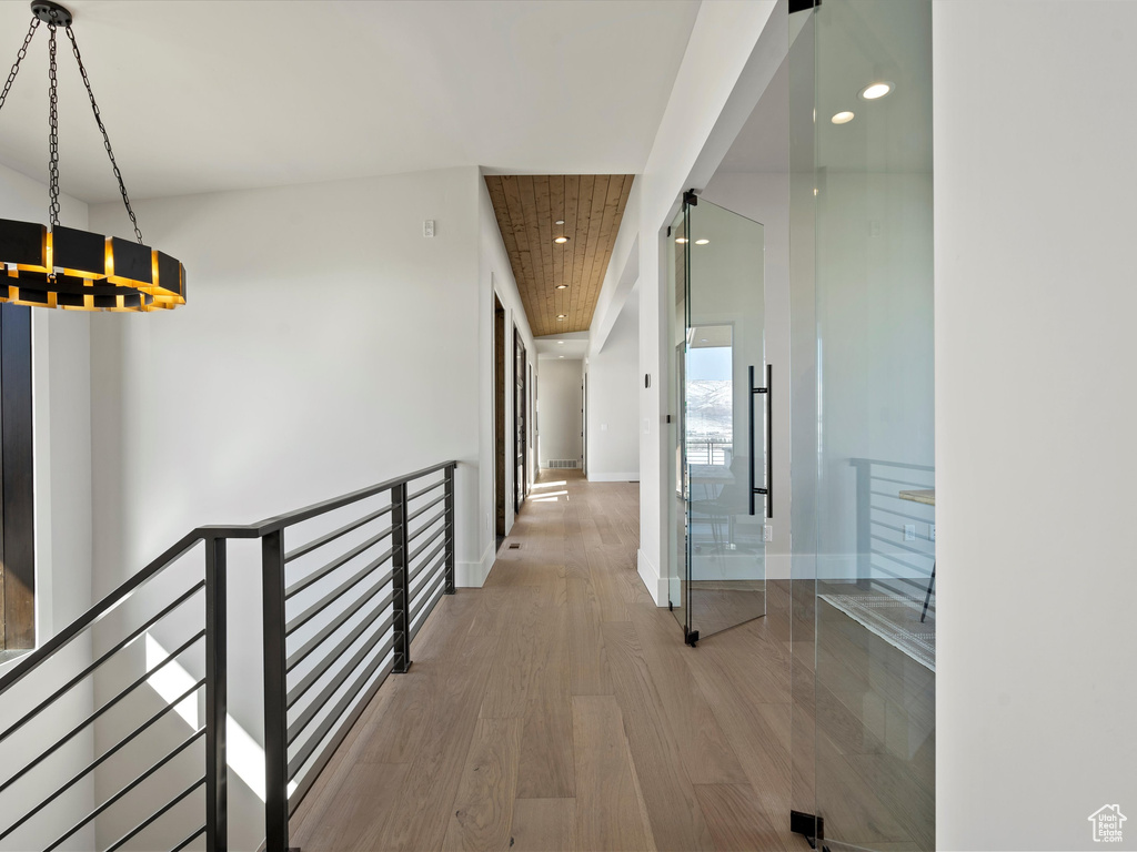 Hall with an upstairs landing, baseboards, wood finished floors, and recessed lighting