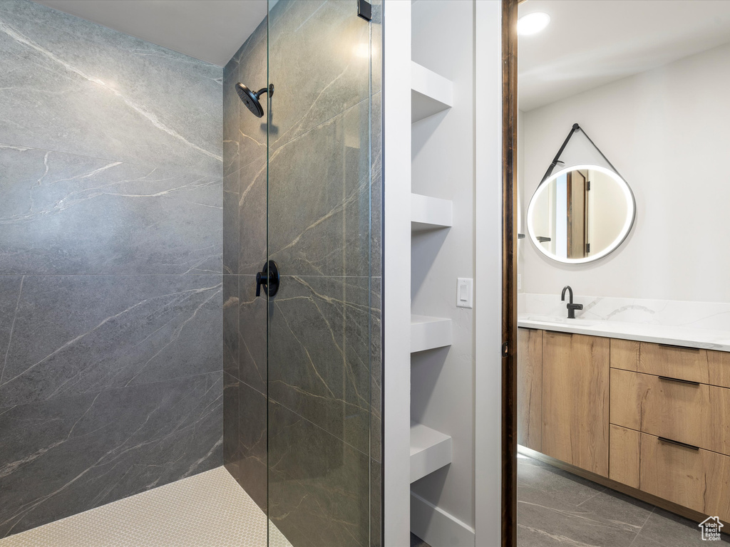 Bathroom featuring tiled shower and vanity