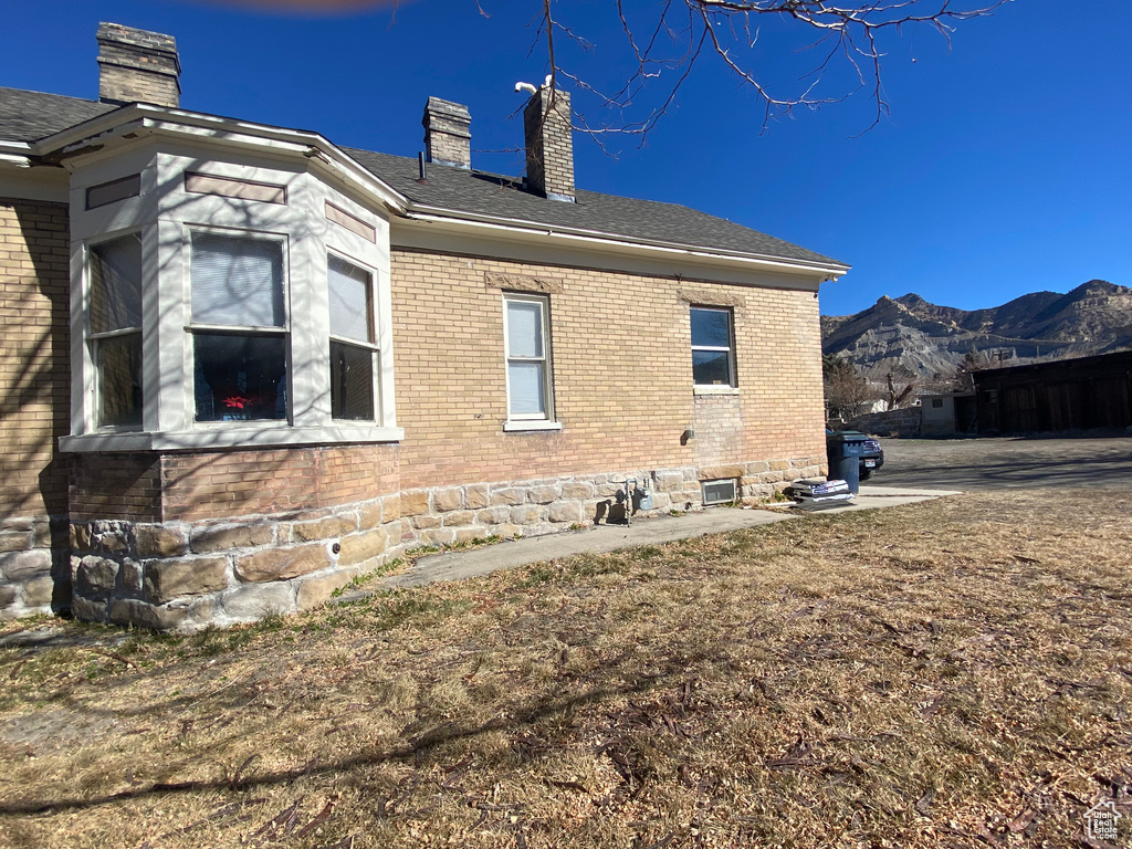 View of property exterior featuring brick siding, a mountain view, and a chimney