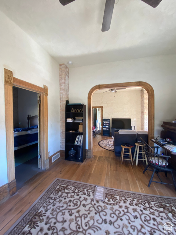 Office area with arched walkways, visible vents, hardwood / wood-style floors, a ceiling fan, and baseboards