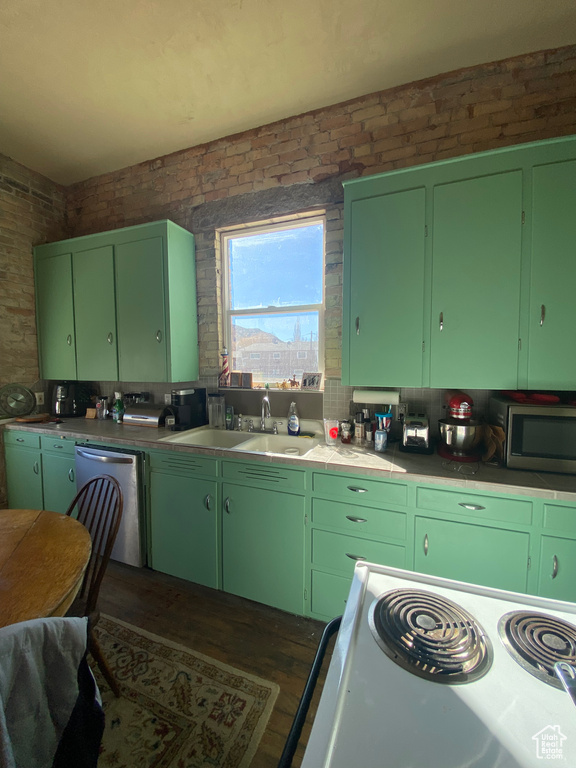 Kitchen featuring white range with electric stovetop, dishwasher, brick wall, stainless steel microwave, and a sink