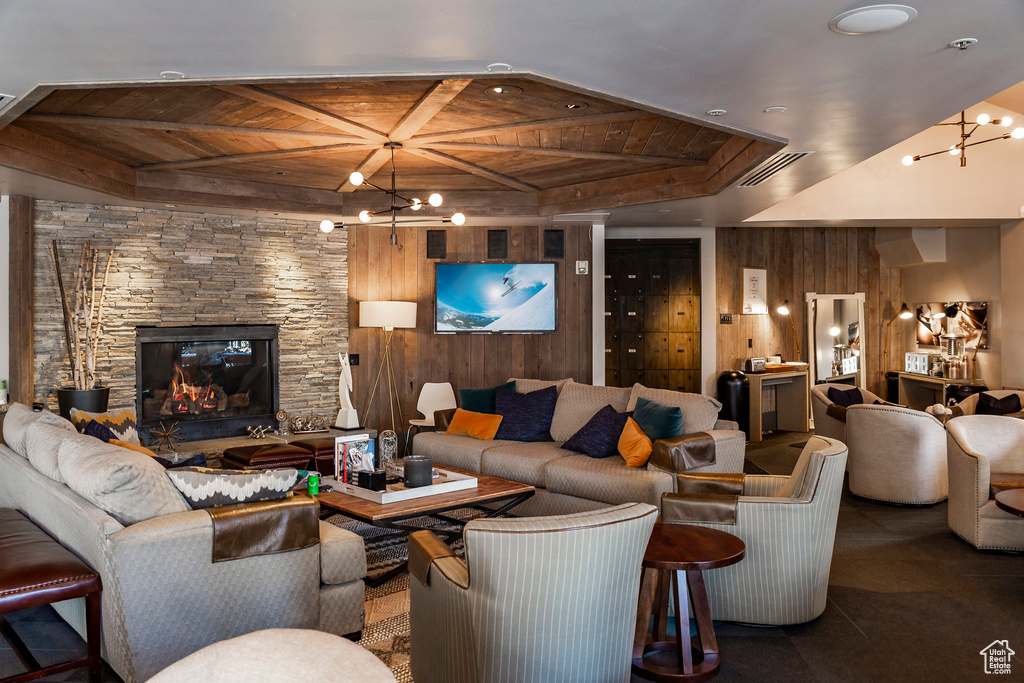 Living room with wood ceiling, a chandelier, wooden walls, beamed ceiling, and a fireplace
