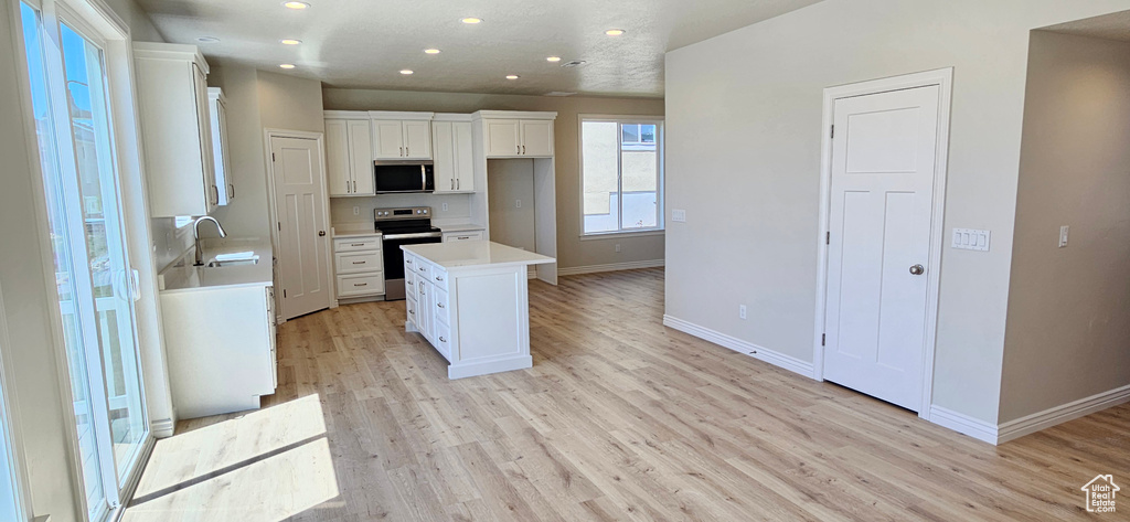 Kitchen featuring white cabinets, appliances with stainless steel finishes, a sink, recessed lighting, and baseboards