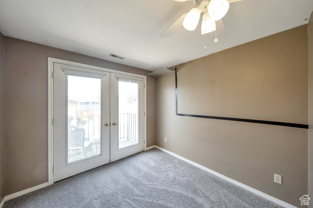 Carpeted empty room featuring baseboards, visible vents, a ceiling fan, and french doors