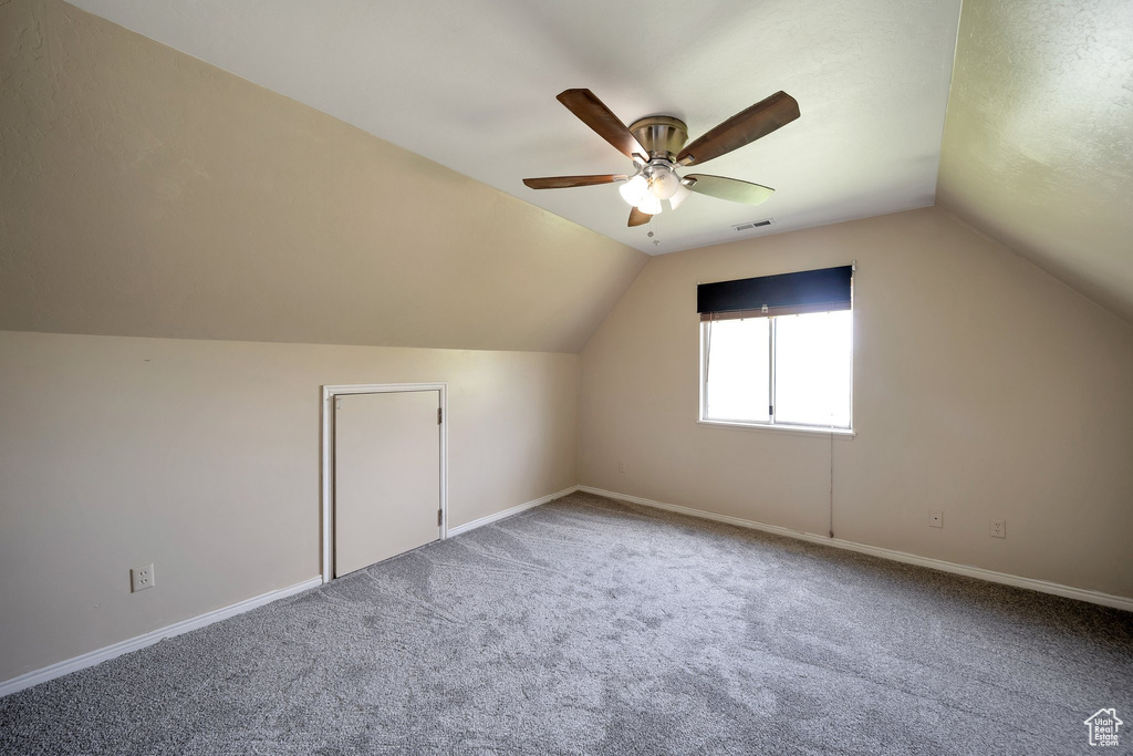 Additional living space with lofted ceiling, carpet flooring, visible vents, baseboards, and a ceiling fan