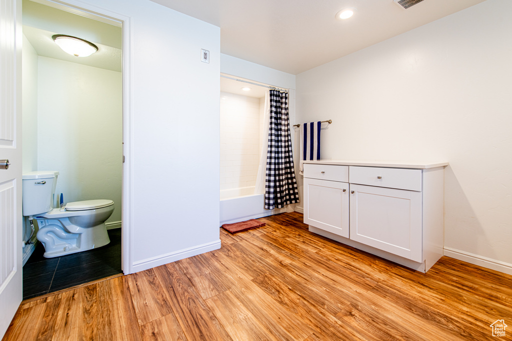 Interior space featuring shower / bath combo with shower curtain, baseboards, toilet, and wood finished floors