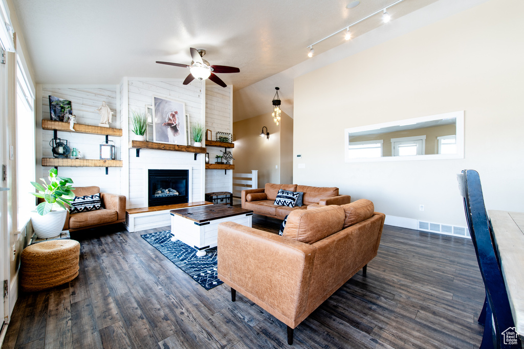 Living room featuring lofted ceiling, a large fireplace, visible vents, and dark wood finished floors