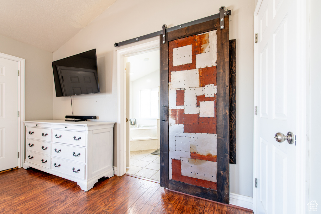 Corridor with lofted ceiling, a barn door, and dark wood finished floors