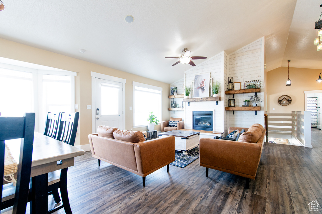 Living room with dark wood-style floors, a fireplace, vaulted ceiling, and ceiling fan