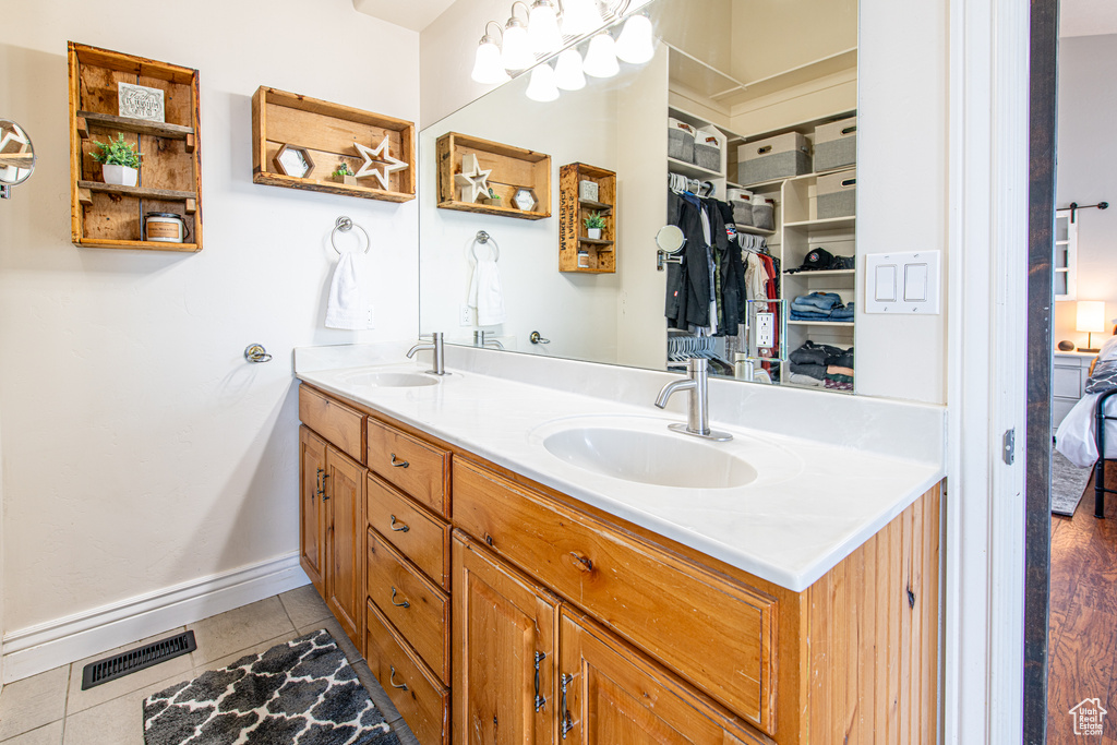 Ensuite bathroom featuring double vanity, tile patterned flooring, a sink, and visible vents